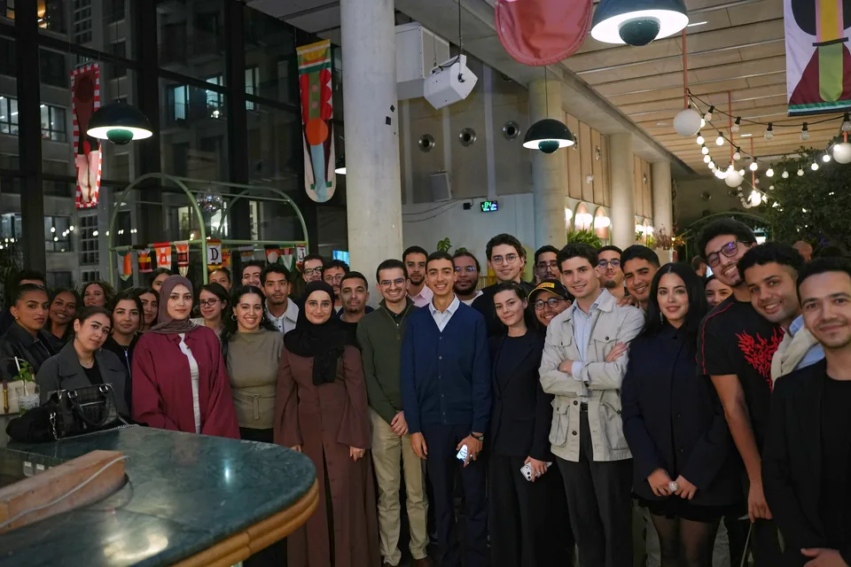 Many guests gathered for a group photo beneath pendant lamps and colourful banners.