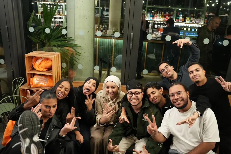 A large group of guests poses joyfully, pulling faces and making hand signs.